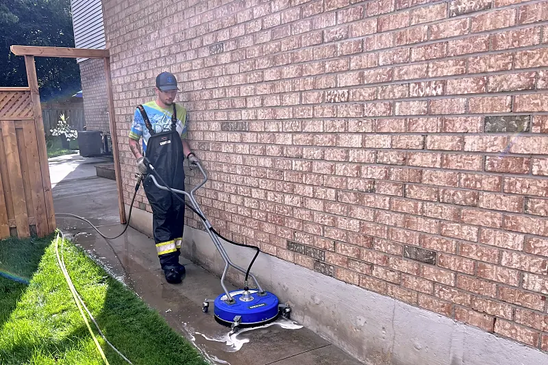 DSS technician pressure washing a concrete walkway with a surface cleaner