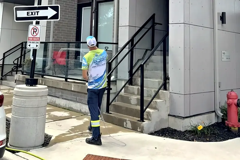 DSS technician rinsing the entrance and glass railings of a townhouse building