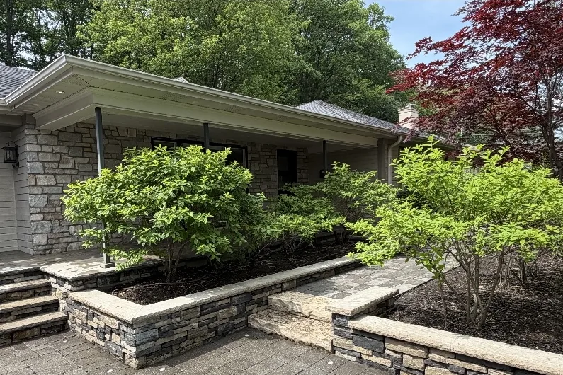 After: The same interlock walkway and stone walls clean after pressure washing